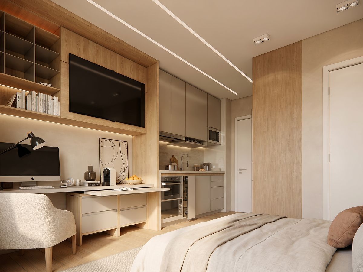 Studio decorado em tons claros, com bancada de trabalho, TV e cozinha integrada